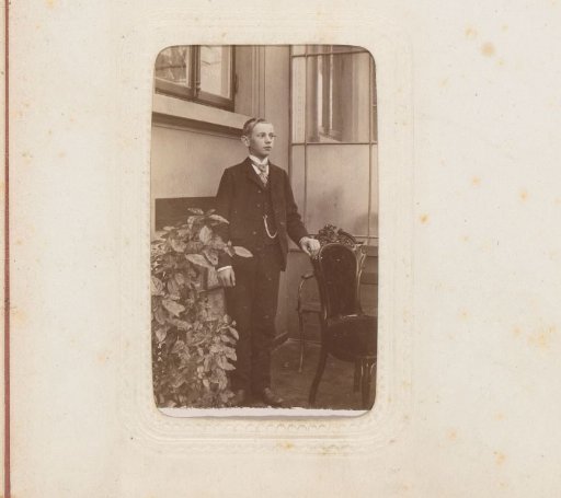Portrait of a boy standing by a chair