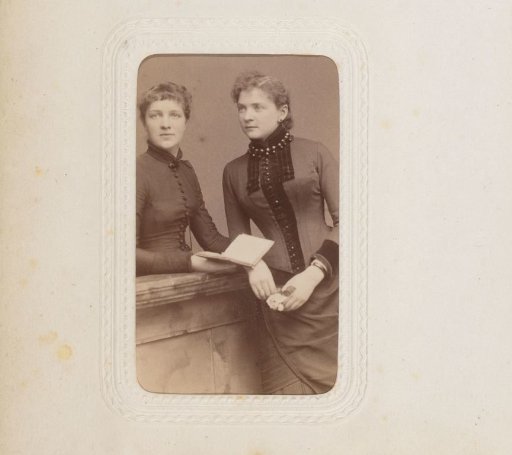 Portrait of two young women leaning on a balustrade, one holding a book