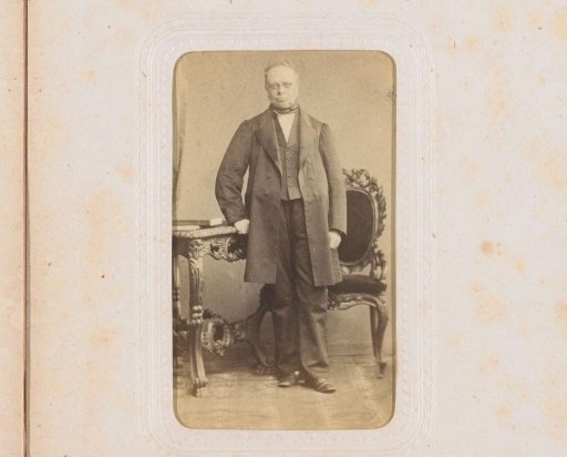 Portrait of a man, standing by a table with books on it