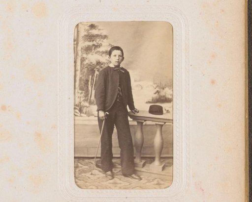 Portrait of a boy with a walking stick in his hand, standing by a balustrade