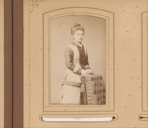 Portrait of a young woman standing beside a chair