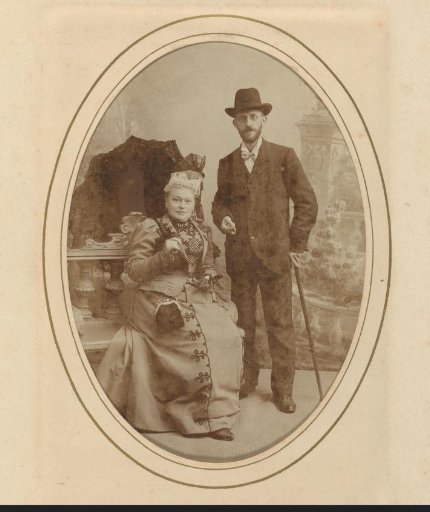 Portrait of a standing man with a walking stick and hat and a seated woman with a parasol