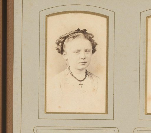 Portrait of a girl with a necklace featuring a cross and a bow in her hair