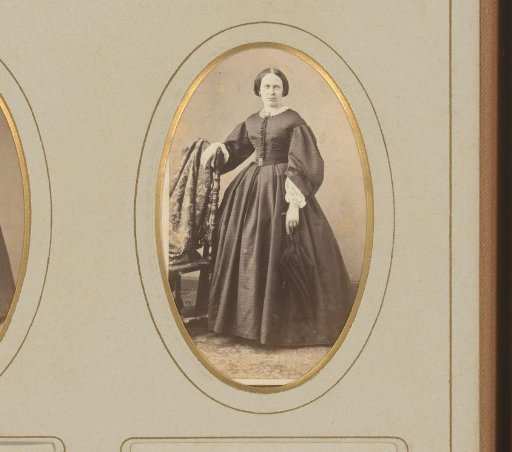 Portrait of a woman with an umbrella in her hand, standing by a chair