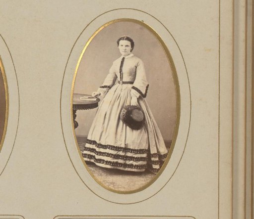 Portrait of a standing woman with a hat in her hand, her hand on a book