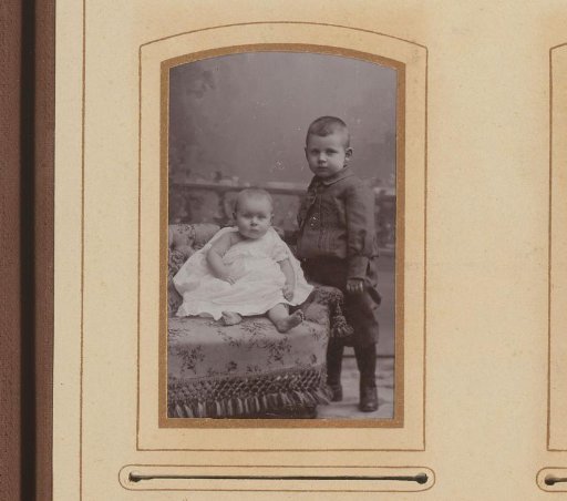 Portrait of a standing boy beside a seated baby