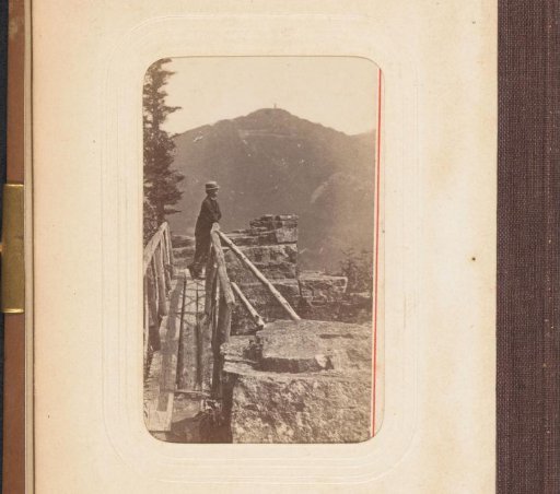 Man on a wooden bridge with mountains in the background
