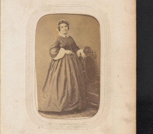 Portrait of a standing woman with a cap by a chair
