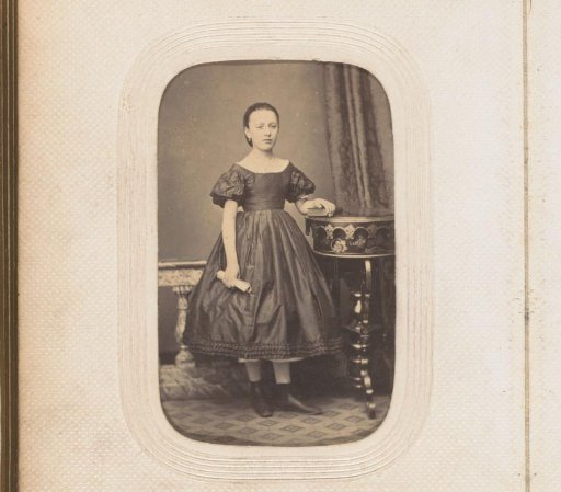 Portrait of a standing girl with a fan by a table
