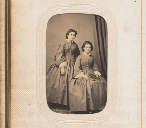 Portrait of two girls, one sitting with a book