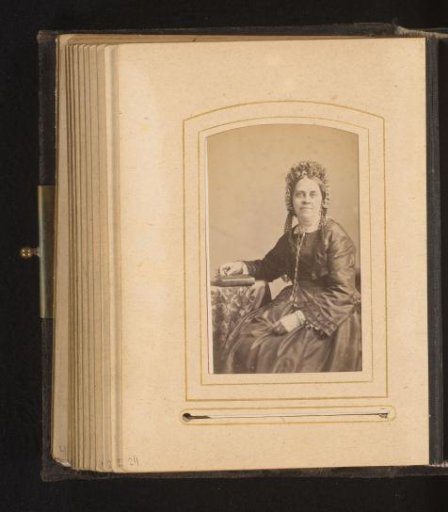 Portrait of a seated woman with a cap and book