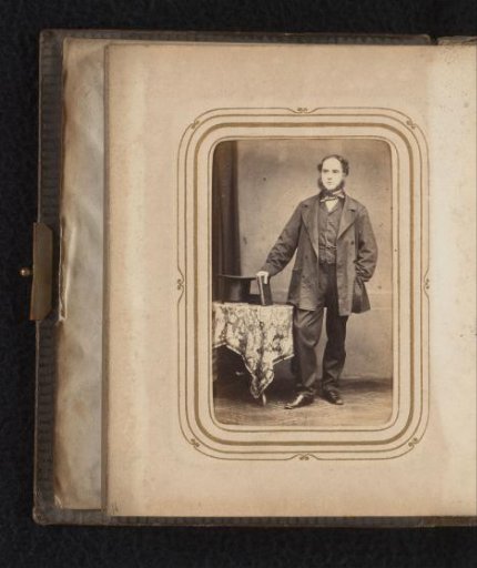 Portrait of a Man with Sideburns, Standing by a Table with a Book and Hat