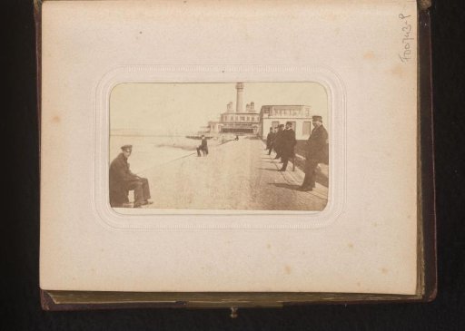 Men on a pier, with a lighthouse in the background
