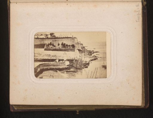 View of the ramparts of a seaside town with ships in the harbor