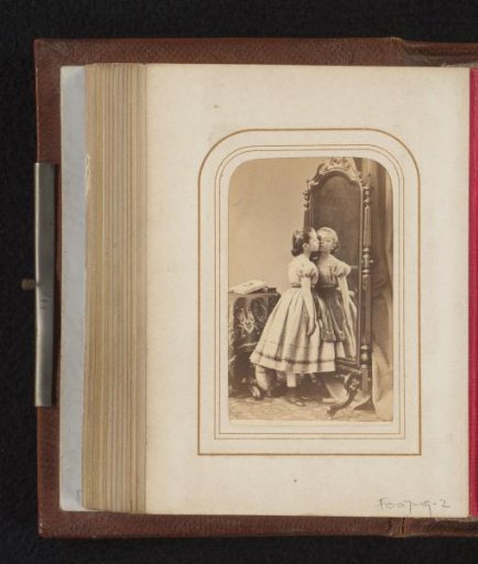 Girl in dress, standing against a mirror