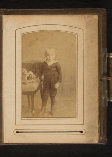 Portrait of a boy, standing by a chair