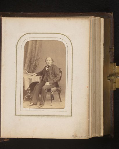 Portrait of a man with sideburns, seated at a table