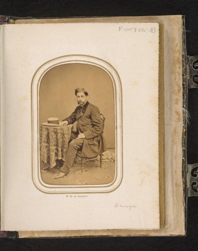 Portrait of a seated man at a table with a hat