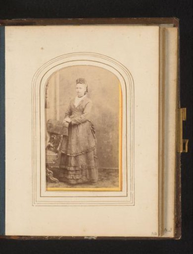Portrait of a woman, standing by a chair