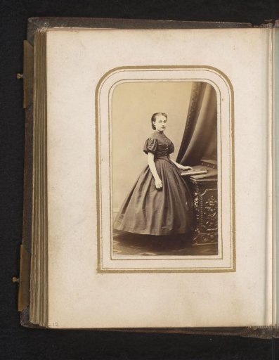 Portrait of a Young Woman Standing by a Piece of Furniture with a Book