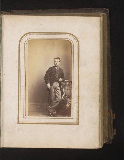 Portrait of a man with a walking stick, standing by a chair