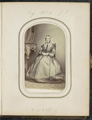 Portrait of a seated woman with a cap by a table with books, inscribed J.K.