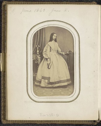 Portrait of a woman with a book in her hand by a table, inscribed Jane K.