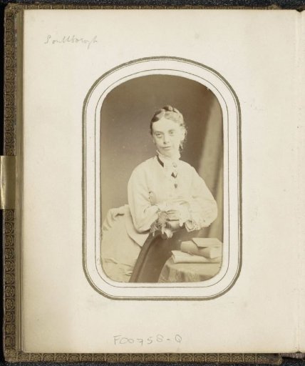 Portrait of a woman leaning on an armchair at a table with books