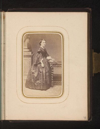 Portrait of a woman standing by a desk with books