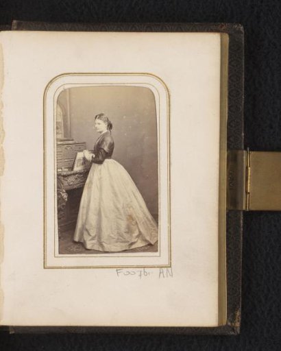 Portrait of a woman, standing by a bookcase
