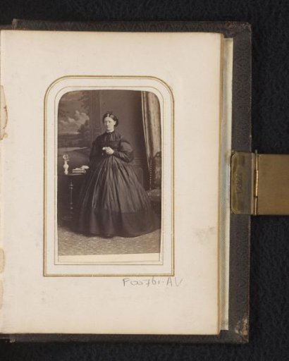 Portrait of a woman, standing by a table with a book and vase