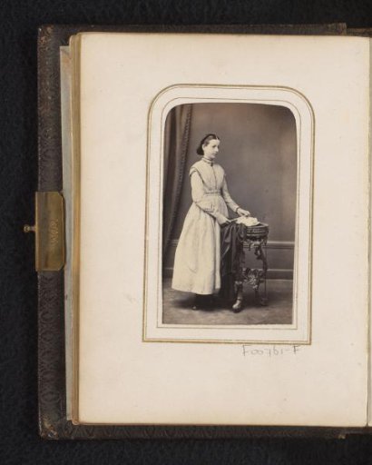 Portrait of a young woman, standing by a table