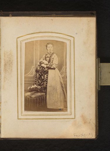 Portrait of a woman, standing by a chair