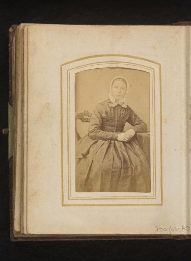 Portrait of a seated woman with a white cap