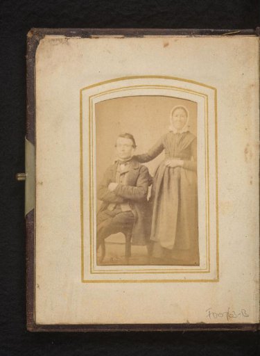 Portrait of a seated man and a standing woman with a white costume cap