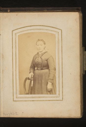 Portrait of a woman, standing by a chair