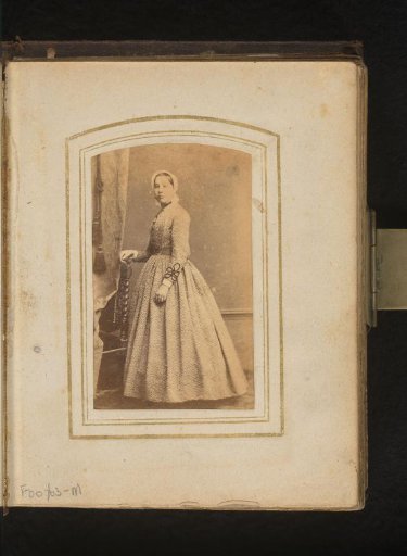 Portrait of a standing woman with a white costume cap