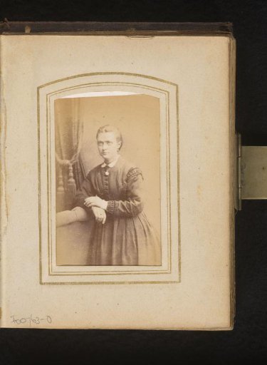 Portrait of a standing young woman, leaning on a chair