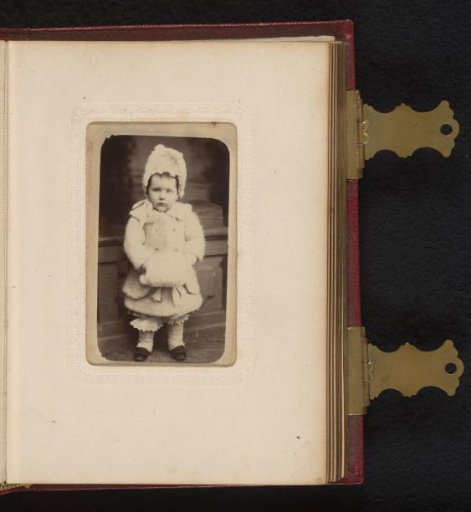 Portrait of a standing toddler with jacket, cap and muff