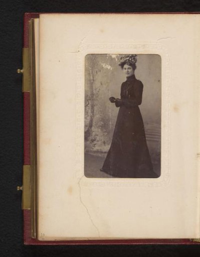 Portrait of a standing woman in a black dress with hat