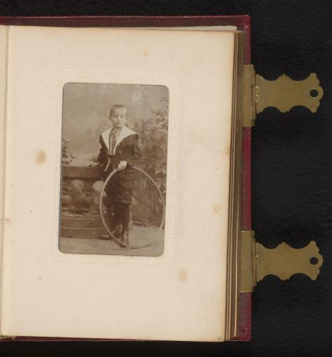 Portrait of a boy with a hoop, standing by a balustrade