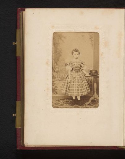 Portrait of a girl, standing by a table with hat