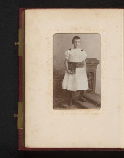 Portrait of a boy in a dress, standing on a staircase by a column