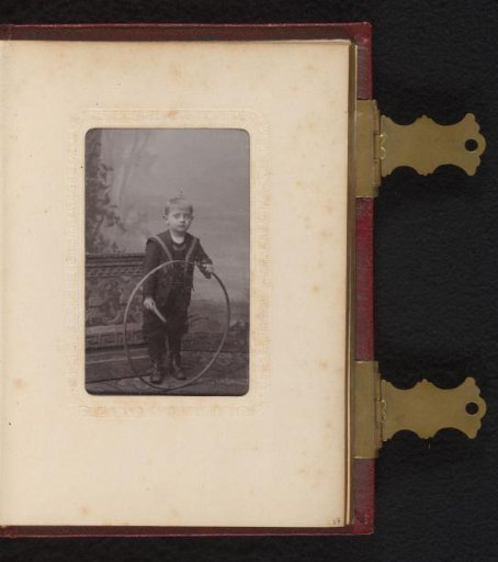 Portrait of a boy with a hoop, standing by a balustrade