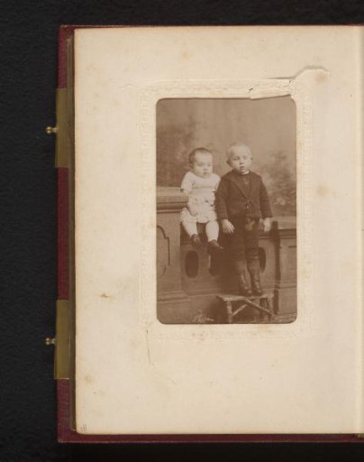 Portrait of a baby and a boy, seated and standing by a balustrade