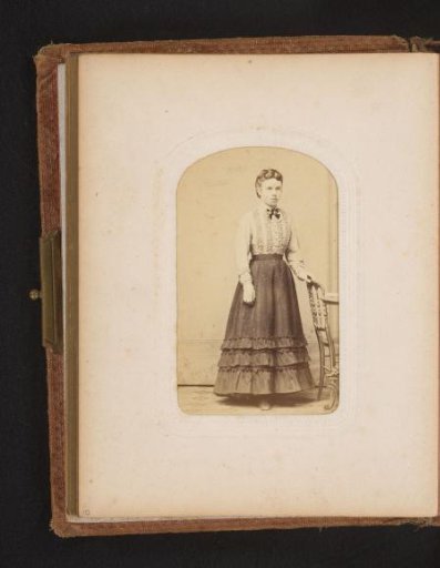Portrait of a young woman standing by a chair