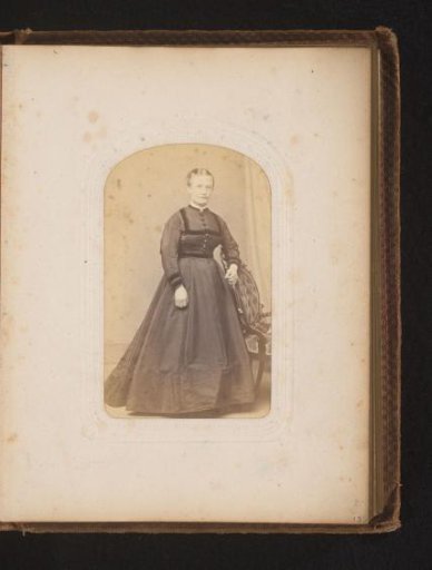 Portrait of a woman standing by a chair