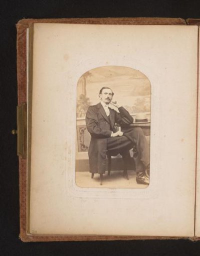 Portrait of a man with a moustache, seated at a table with a hat