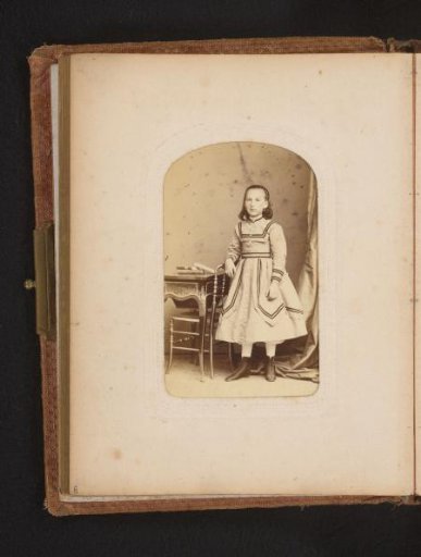 Portrait of a girl standing by a desk and a chair