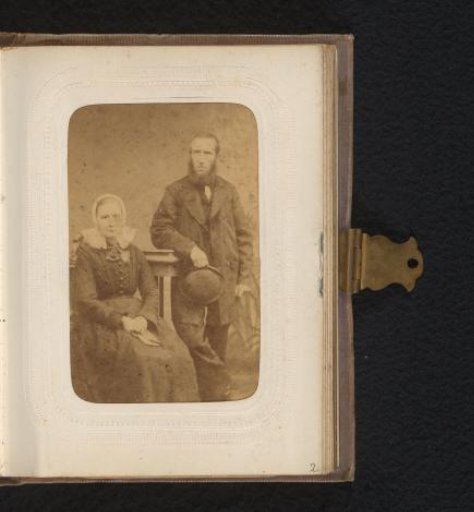 Portrait of a standing man with a hat in his hand and a seated woman